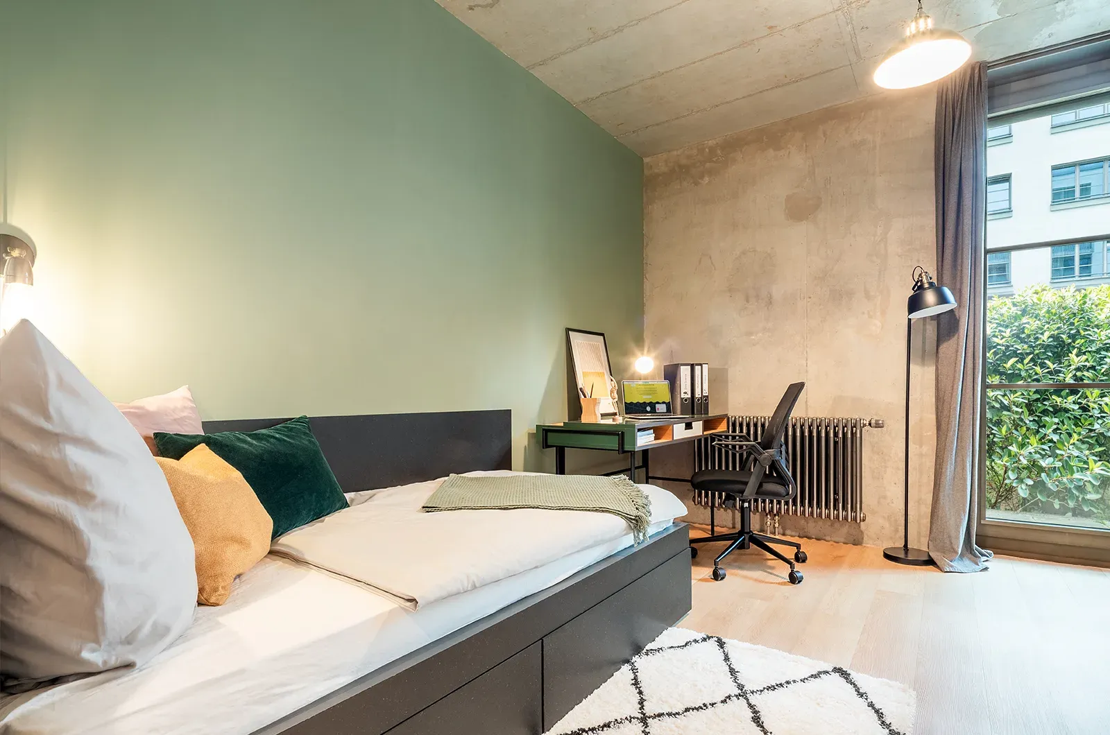 Styled bed and desk area in a Classic Patio Room at Neon Wood Berlin Frankfurter Tor showing decorated workspace and sleeping space with personalization example