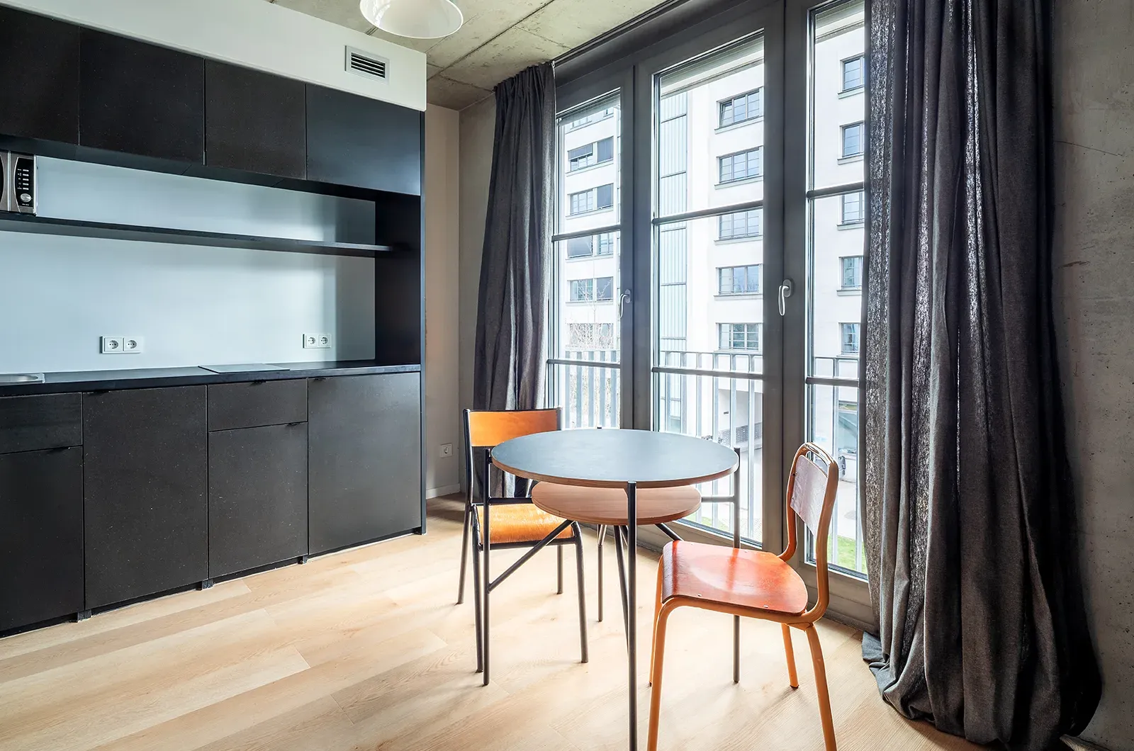 Undecorated kitchen and dining area in a Deluxe Balcony Room at Neon Wood Berlin Frankfurter Tor showing furnished baseline without styling accents