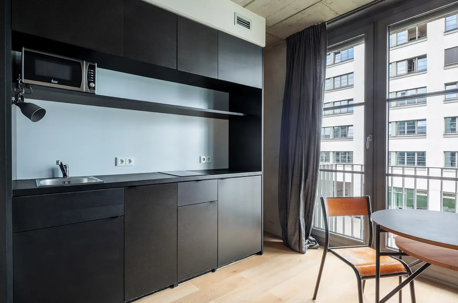 Undecorated close-up of the kitchen in a Deluxe Balcony Room at Neon Wood Berlin Frankfurter Tor showing furnished baseline without styling accents