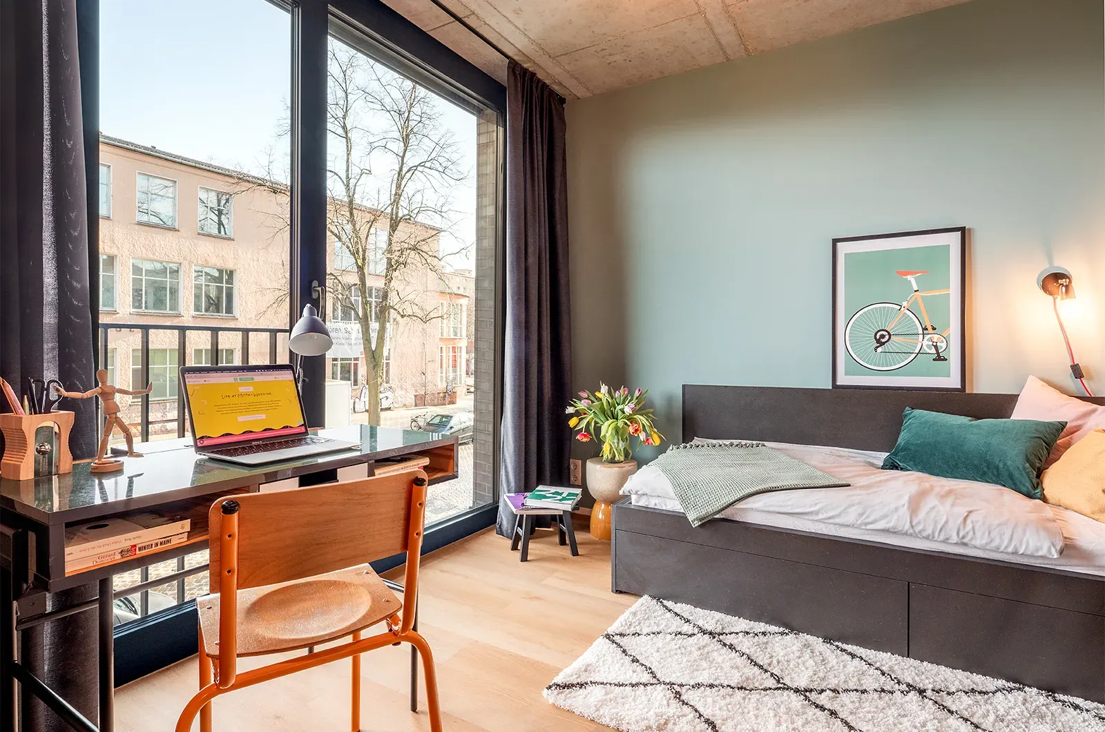 Styled bed, desk and outside view in a Deluxe Room at Neon Wood Berlin Mitte-Wedding showing decorated space and personalization example