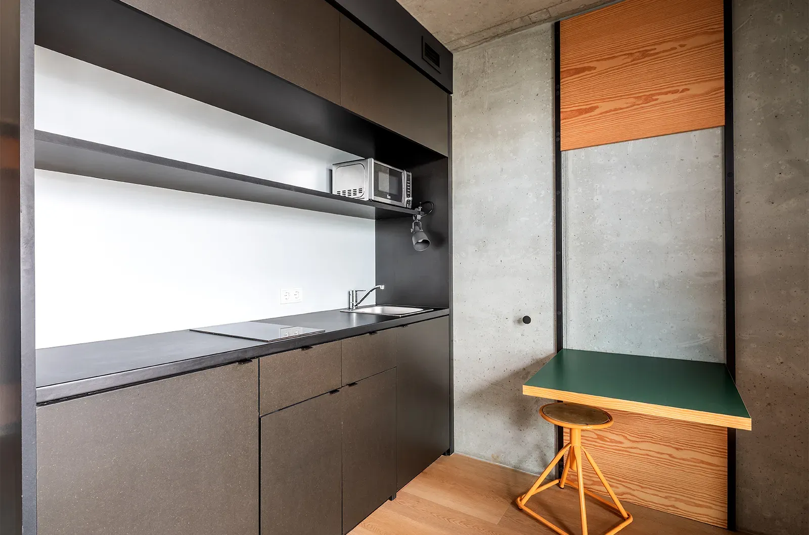 Undecorated kitchenette and foldable table in a Deluxe Room at Neon Wood Berlin Mitte-Wedding showing furnished baseline without styling accents