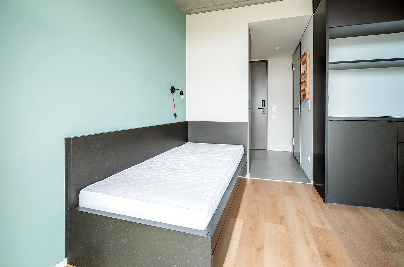 Undecorated bed and entrance area in a Deluxe Balcony Room at Neon Wood Berlin Mitte-Wedding showing furnished baseline without styling accents