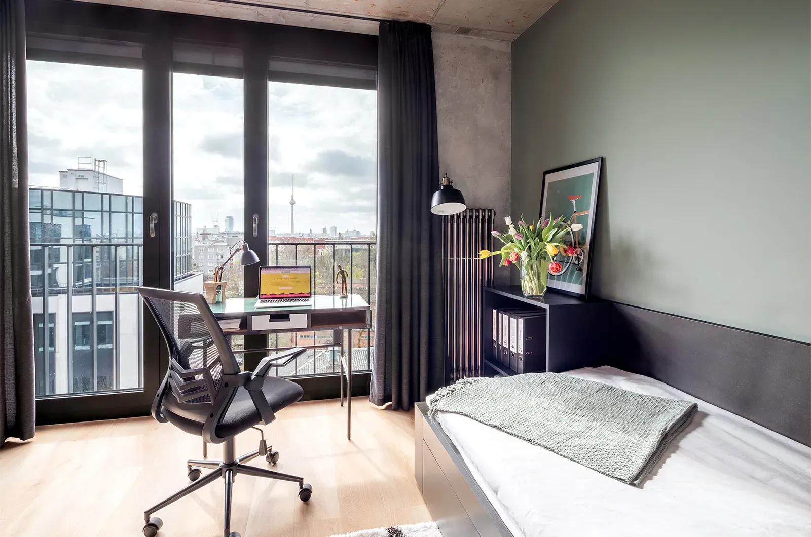 Styled bed, desk and outside view in a Penthouse Room at Neon Wood Berlin Mitte-Wedding showing decorated space and personalization example