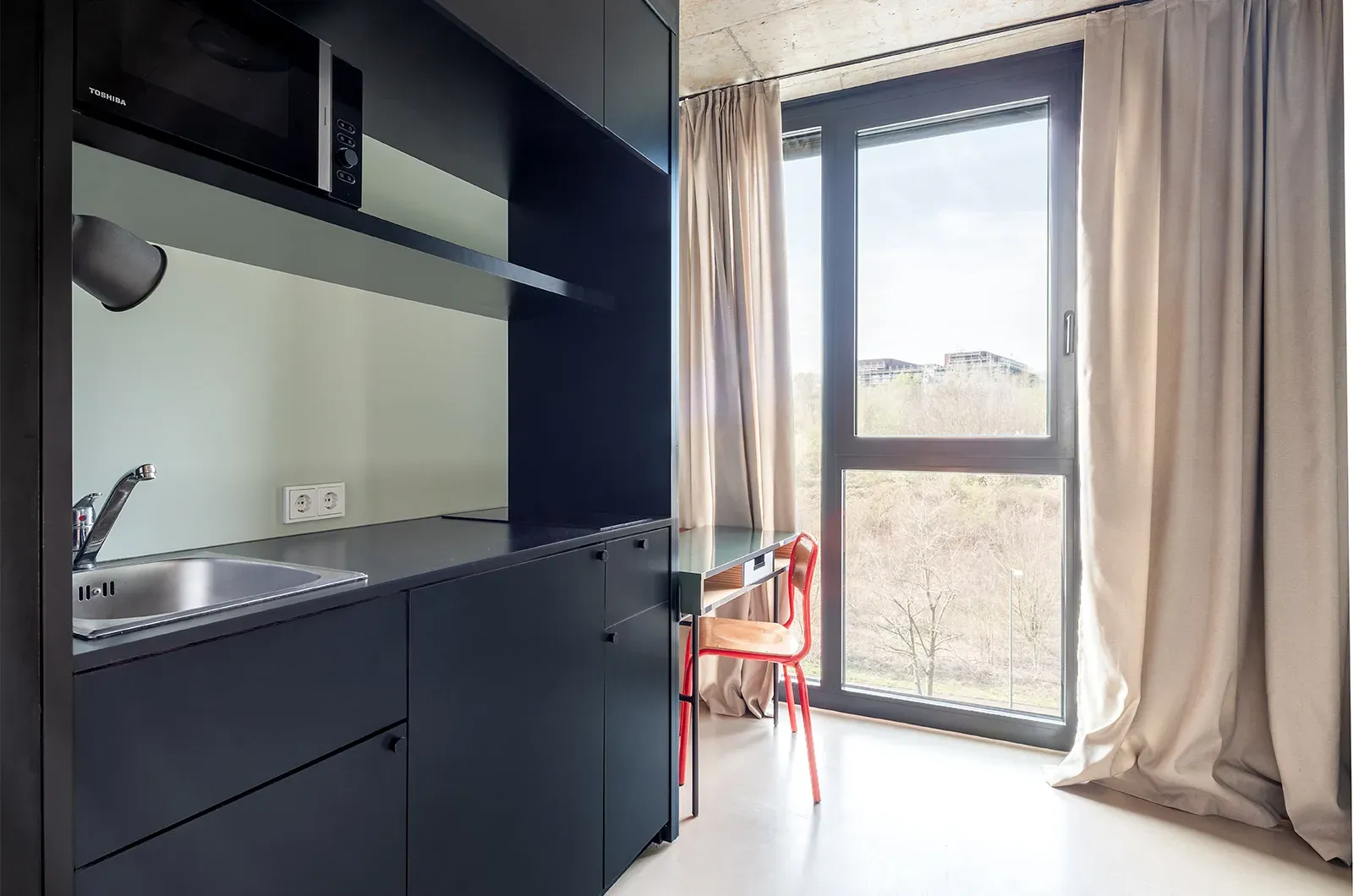 Undecorated kitchen in a Classic Deluxe Room at Neon Wood Frankfurt Riedberg showing furnished baseline without styling accents