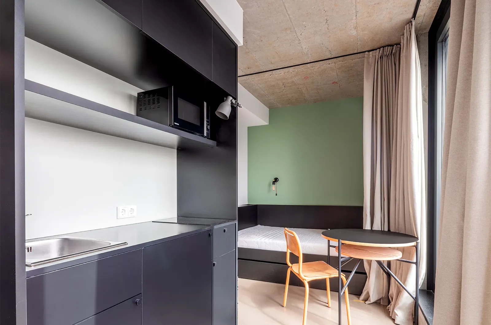 Undecorated kitchenette, dining and bed area in a Penthouse Balcony Room at Neon Wood Frankfurt Riedberg showing furnished baseline without styling accents