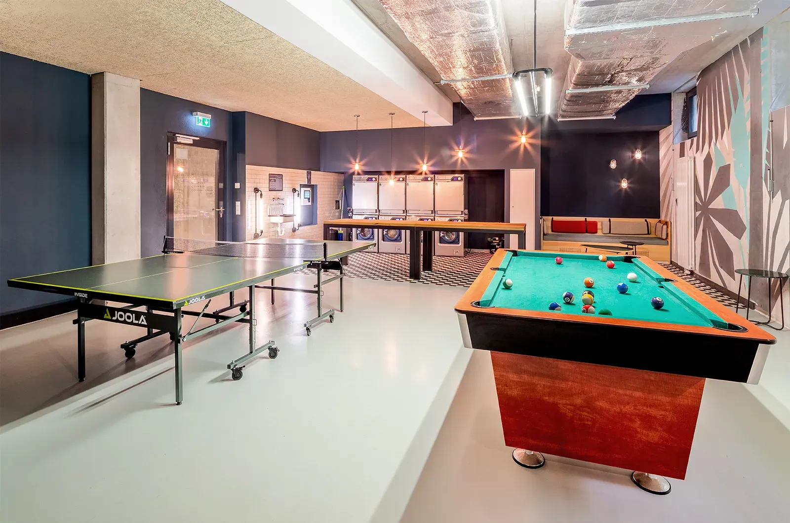 Game room with recreational activities in the laundry area at Neon Wood Berlin Adlershof providing students with entertainment while doing laundry
